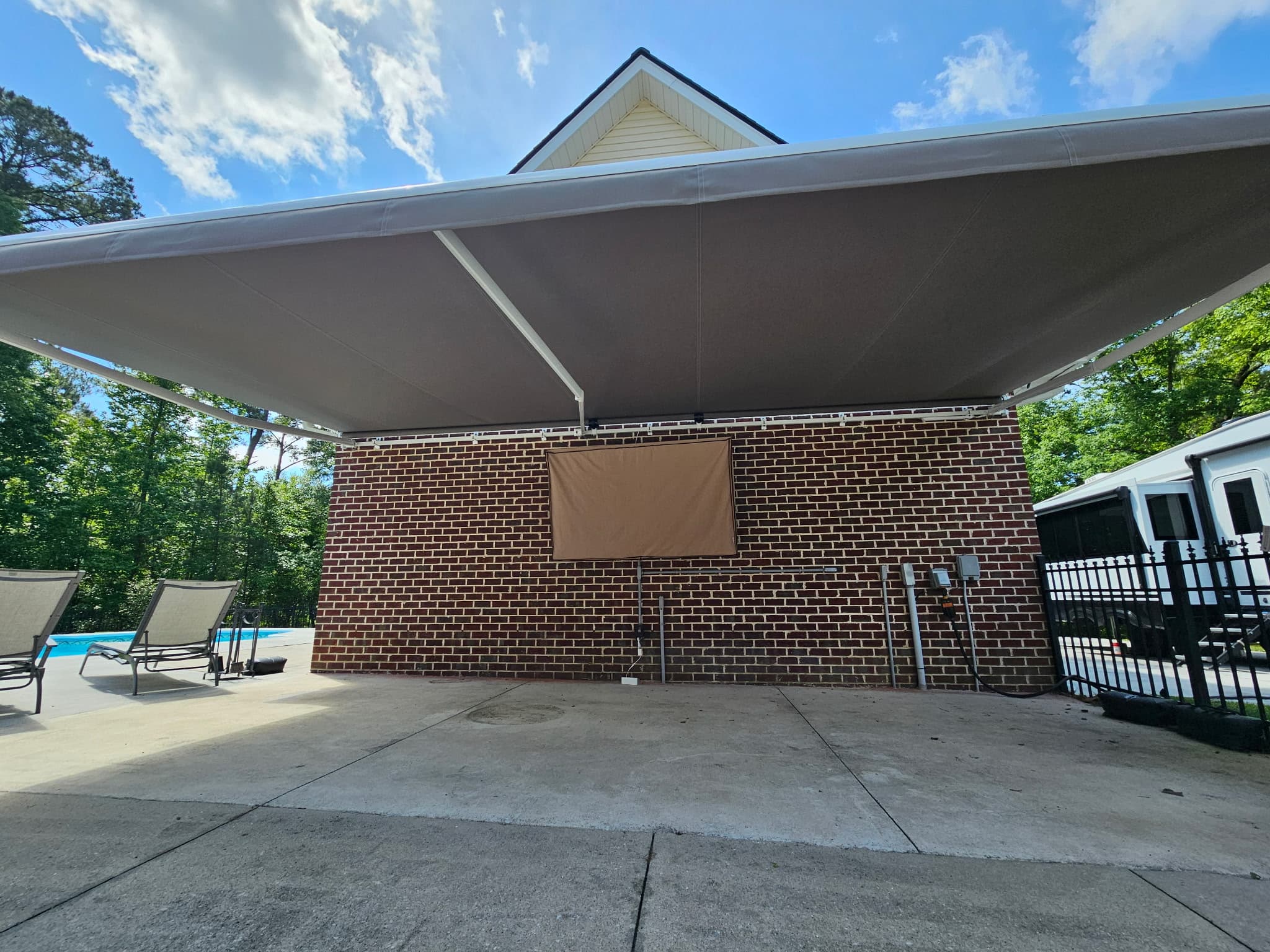 Dramatic view of a retractable awning extended over a pool house patio