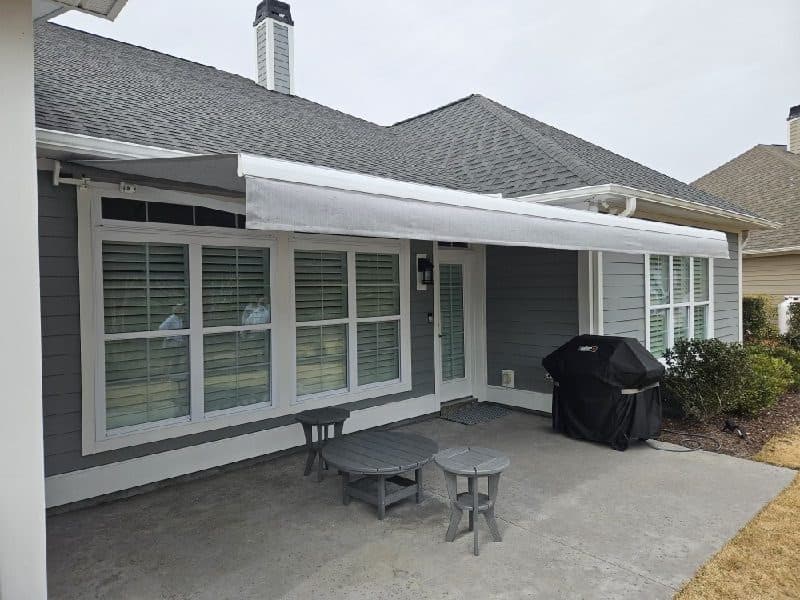 Retractable awning covering a patio on a gray home